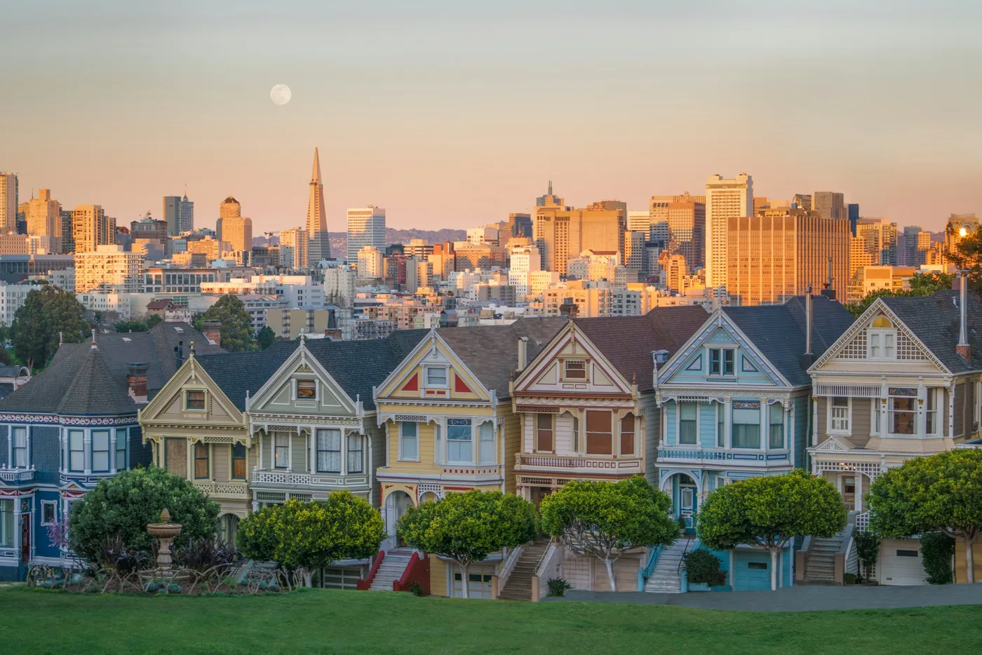 The Painted Ladies, a row of Victorian houses at Alamo Square, with the downtown skyline and a setting moon behind